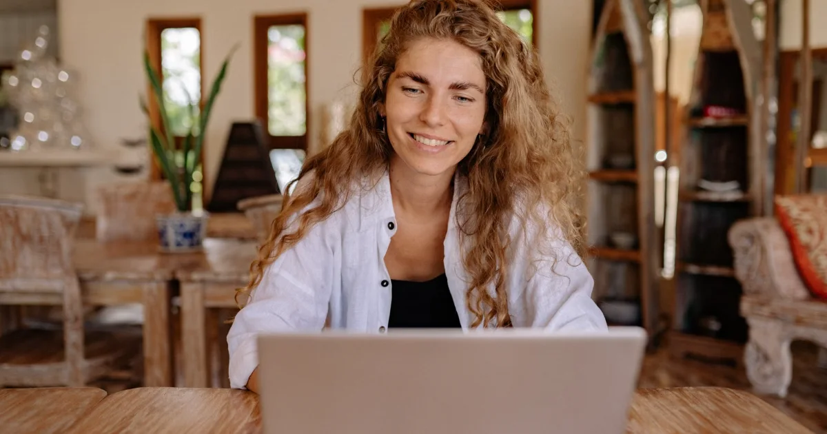 Smiling woman looking at her laptop – Arrests.org removal service by Defamation Defenders