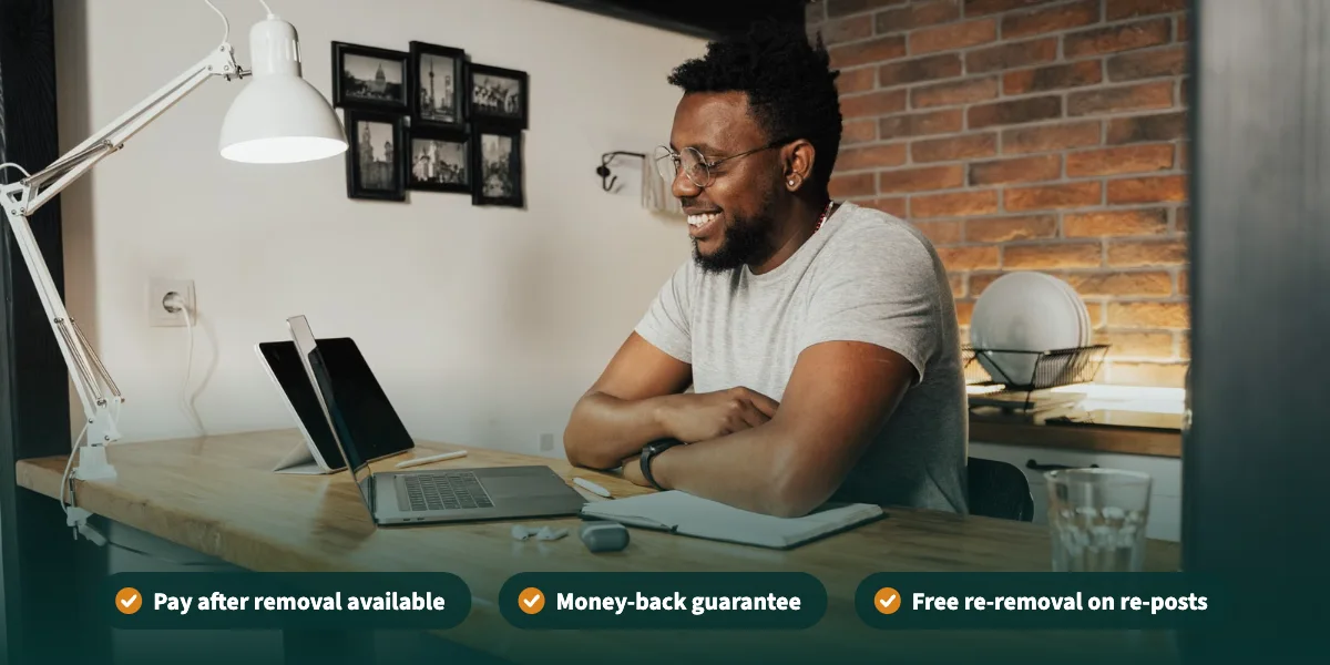 Smiling man looking at his laptop at home, with pay after removal, money-back guarantee, and free re-removal on re-posts