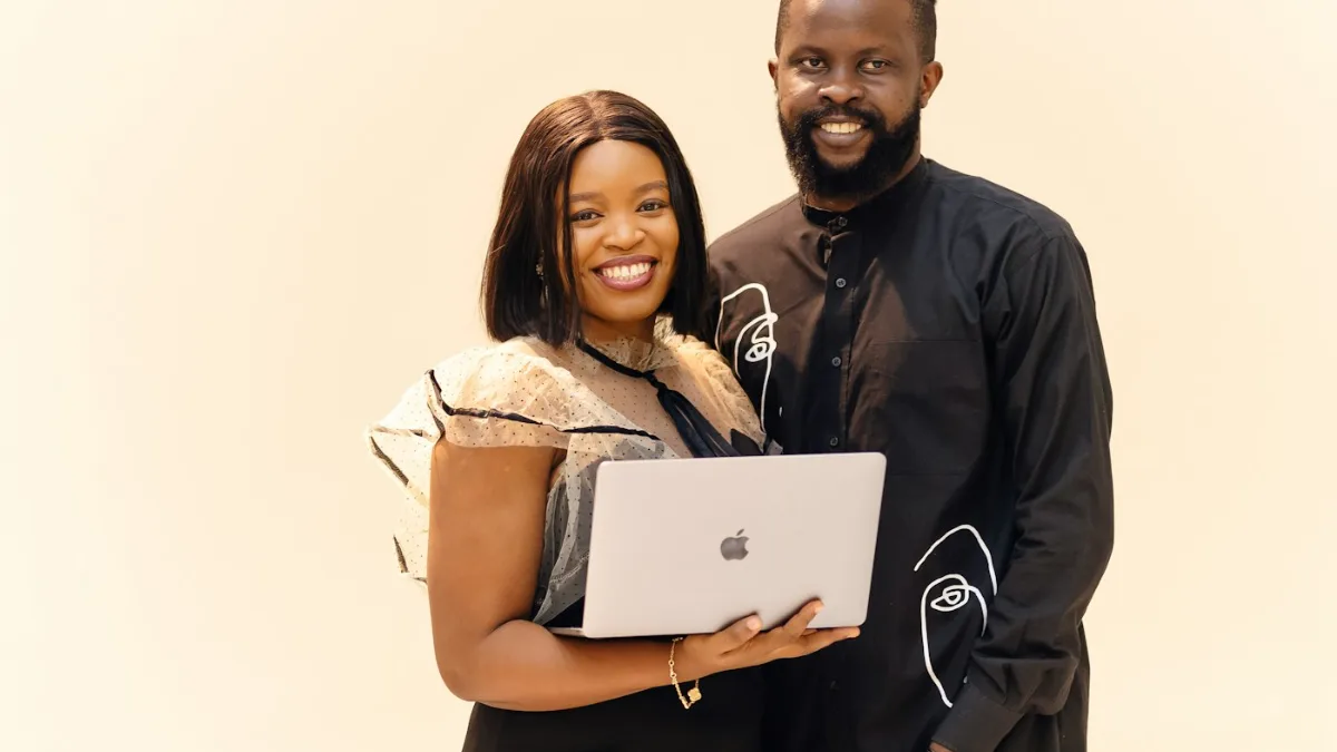 Business couple smiling while holding a laptop after taking control of their online reputation