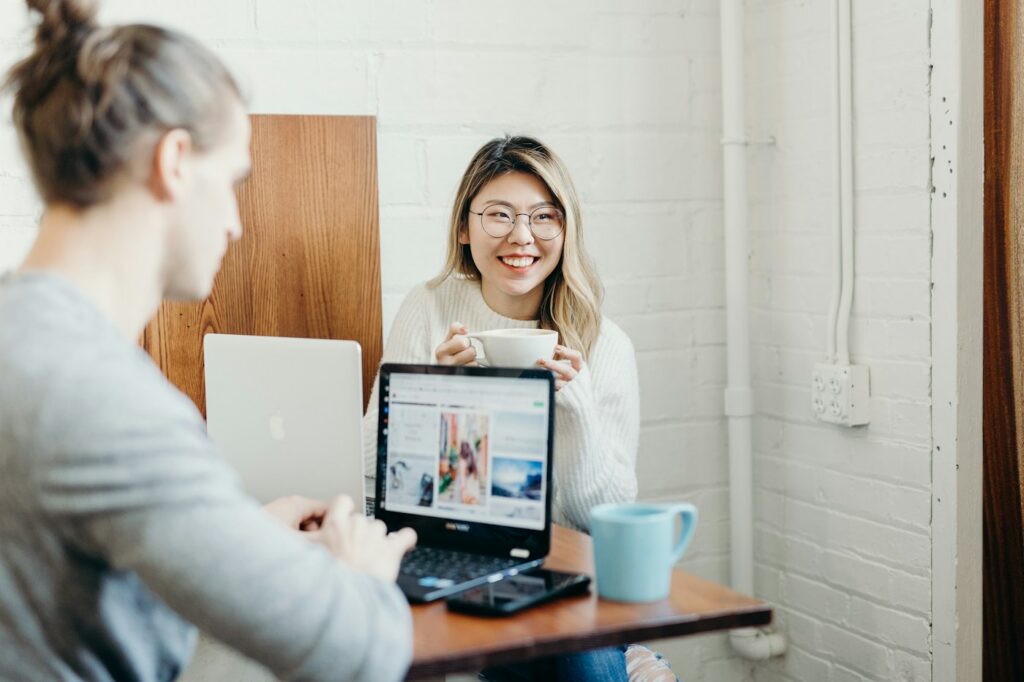 Smiling woman holding a cup at a table with a laptop