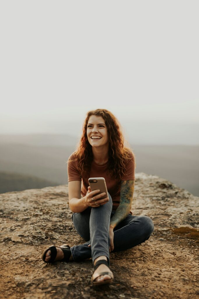 Smiling woman sitting outdoors with her phone