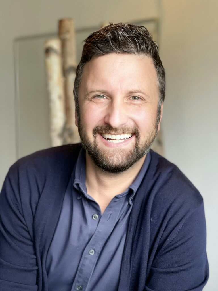 Smiling man with a beard in a blue shirt