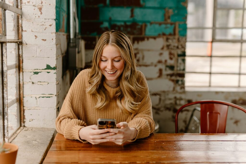 Smiling woman at a table looking at her phone