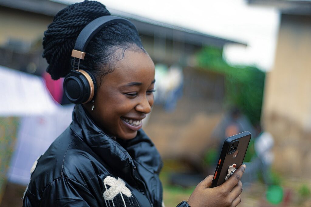 Smiling woman wearing headphones and holding a phone