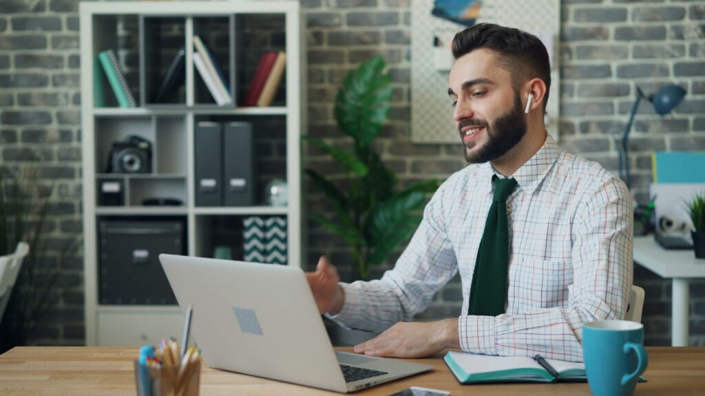 Smiling man at a desk using a laptop