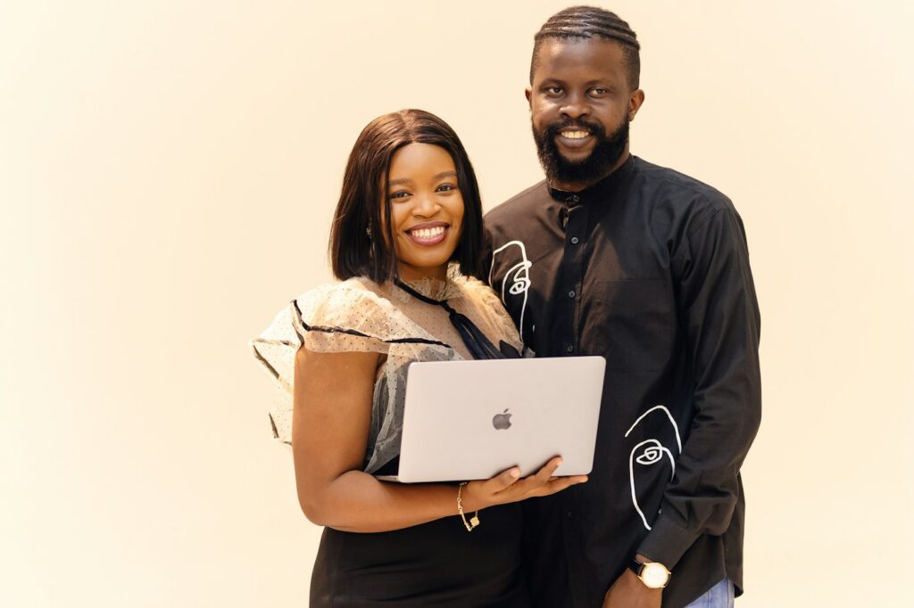 Smiling couple standing together holding a laptop