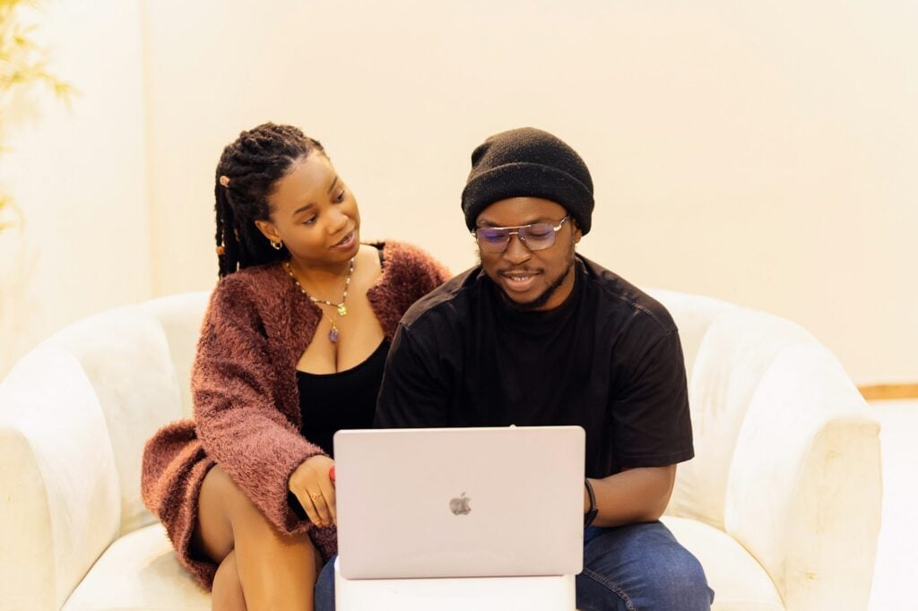 Smiling couple sitting on a couch with a laptop