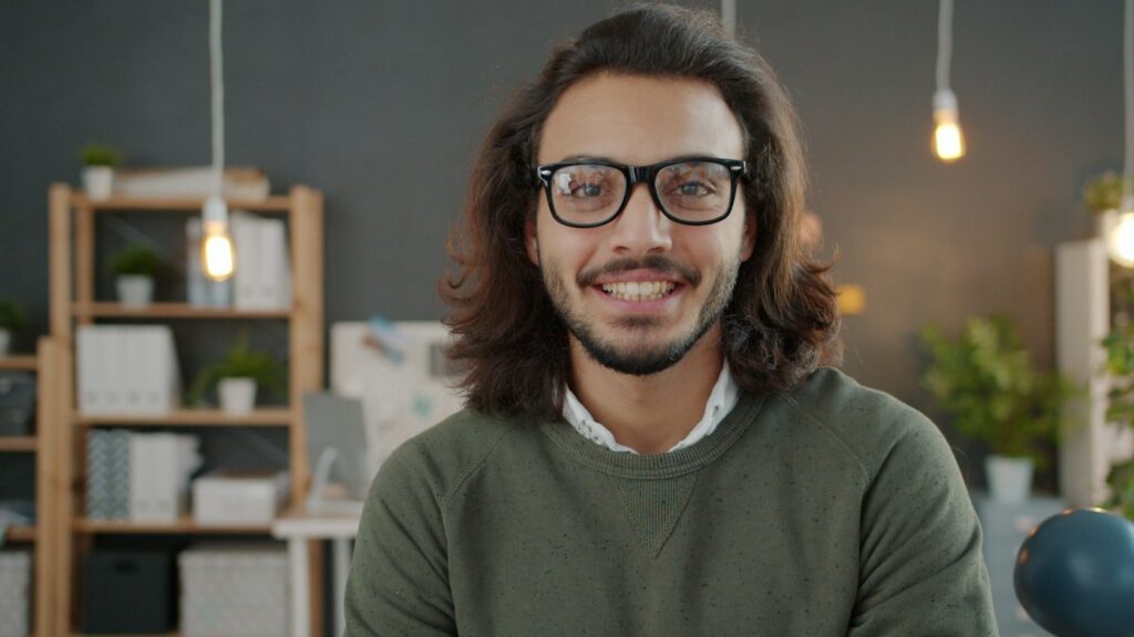 Man with glasses and long hair smiling
