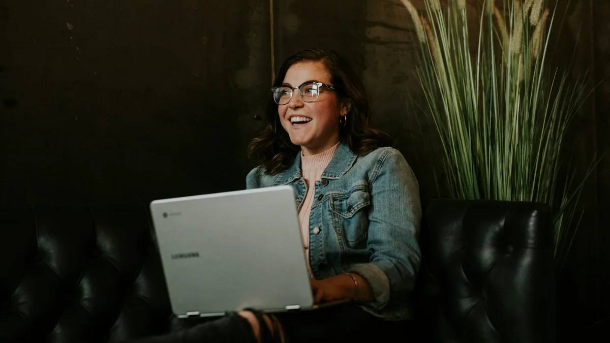 Woman smiling at her laptop after rebuilding her reputation following a whisper network