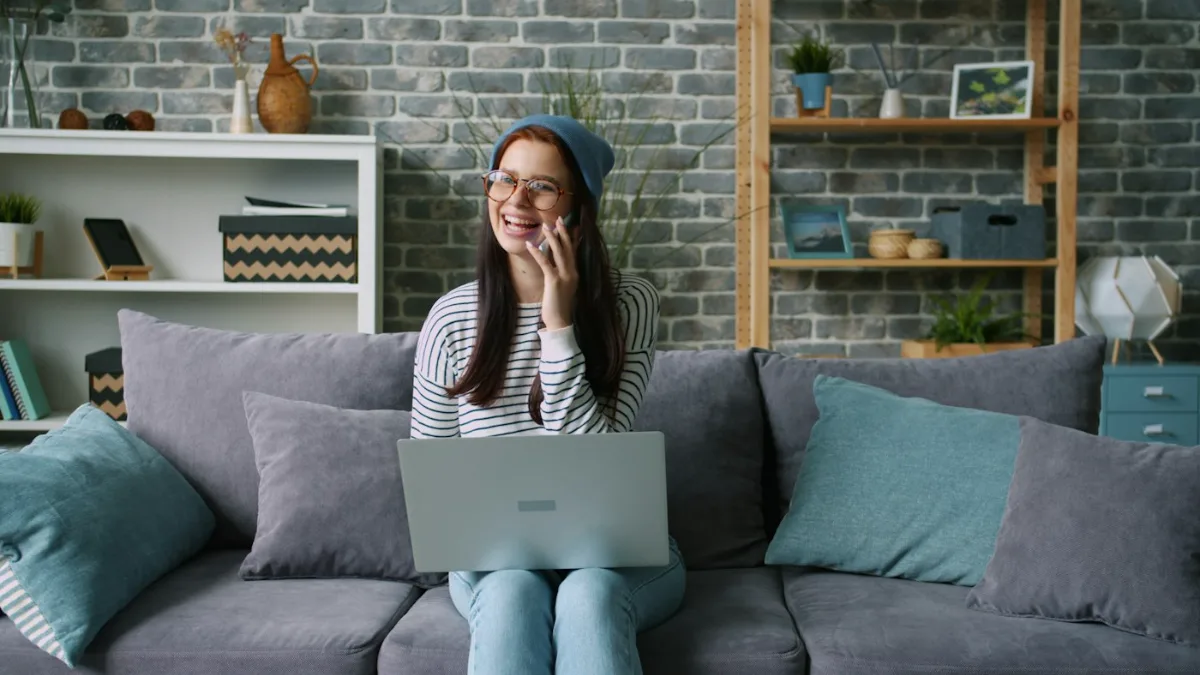 Woman smiling while on the phone with her laptop after defending her online reputation